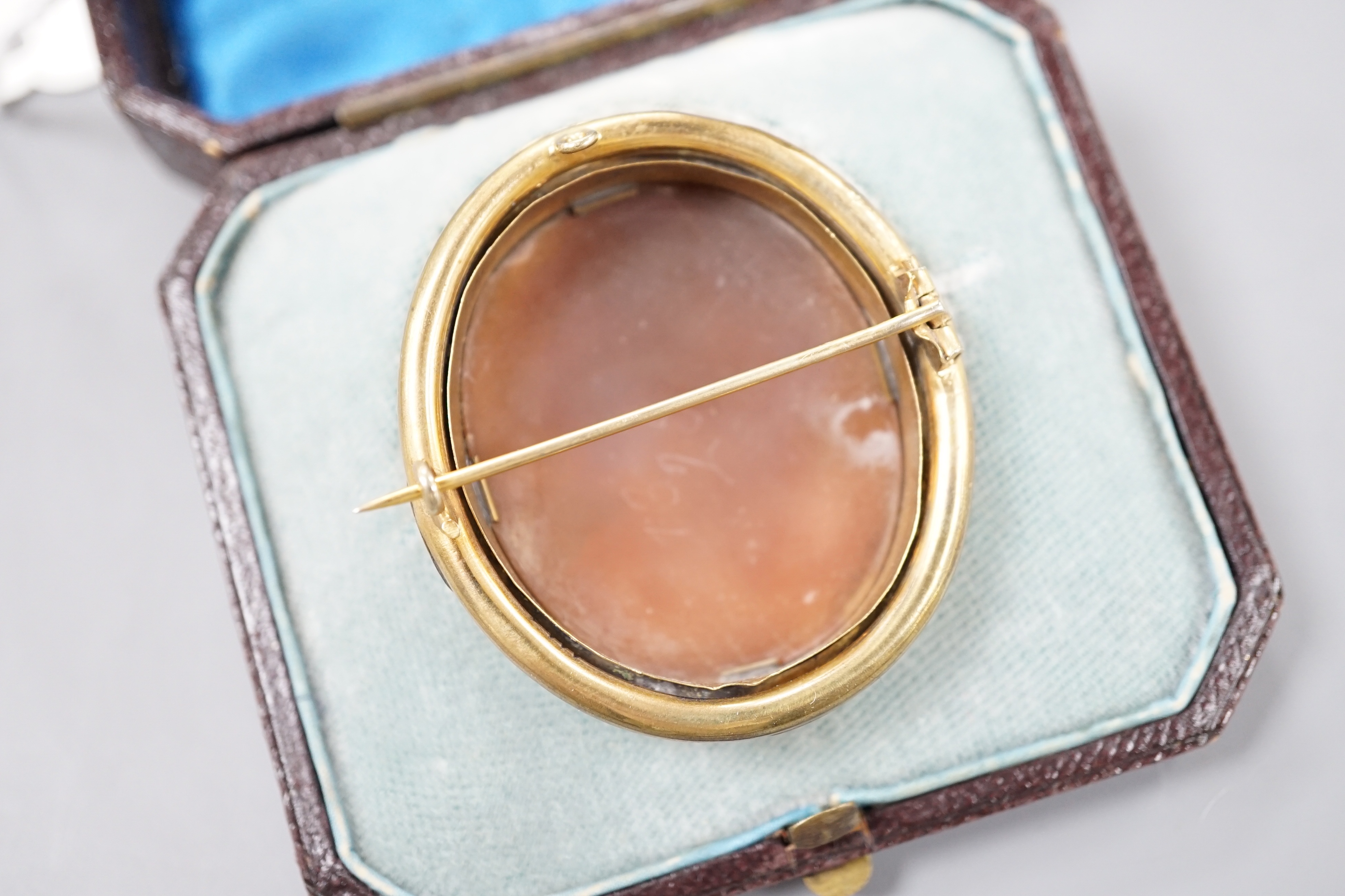 A cased Victorian yellow metal mounted oval cameo shell brooch, carved with the bust of a lady to sinister, 50mm, gross 15.6 grams.